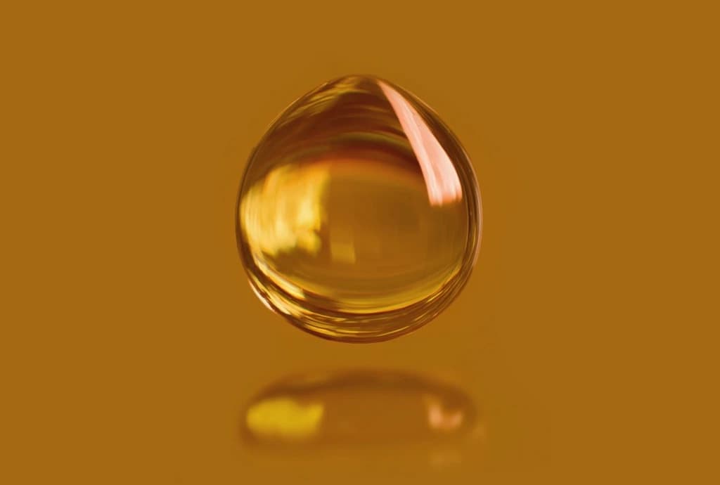A liquid droplet suspended mid-air against an amber background