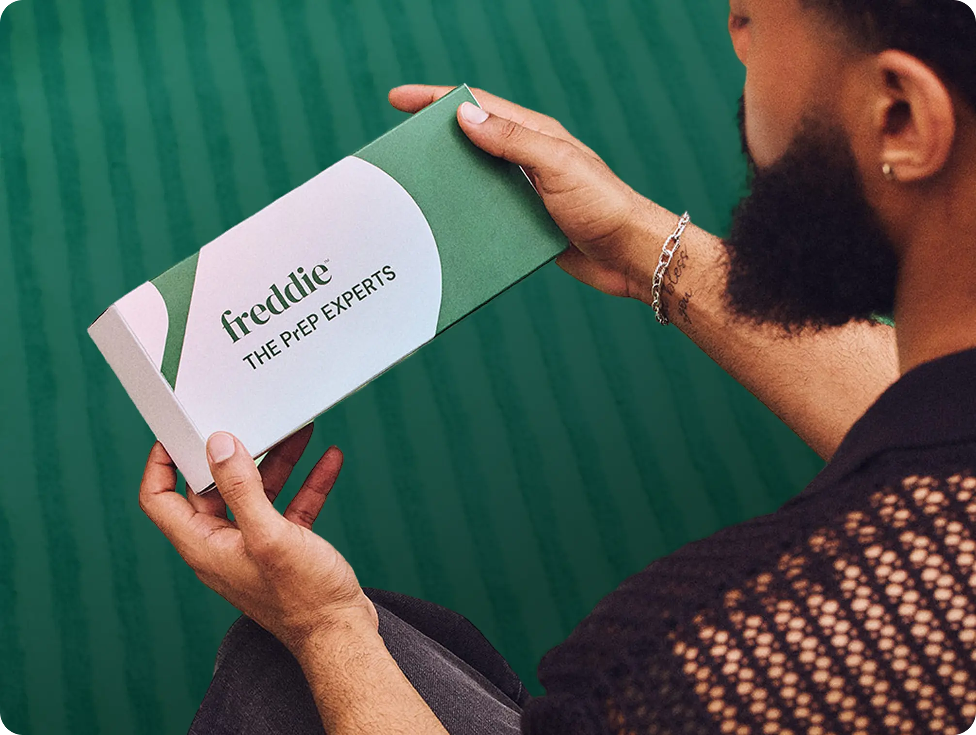 Bearded man holding a green Freddie at-home test kit box labeled 'The PrEP Experts.'